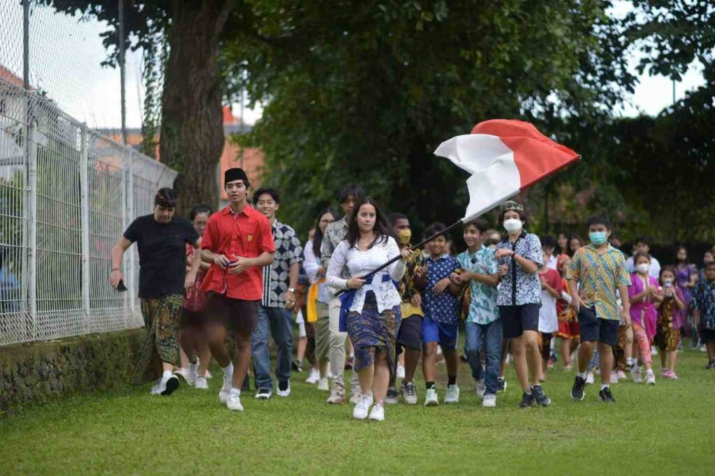 "School students in Bali participating in an Indonesian Independence Day parade with flags"