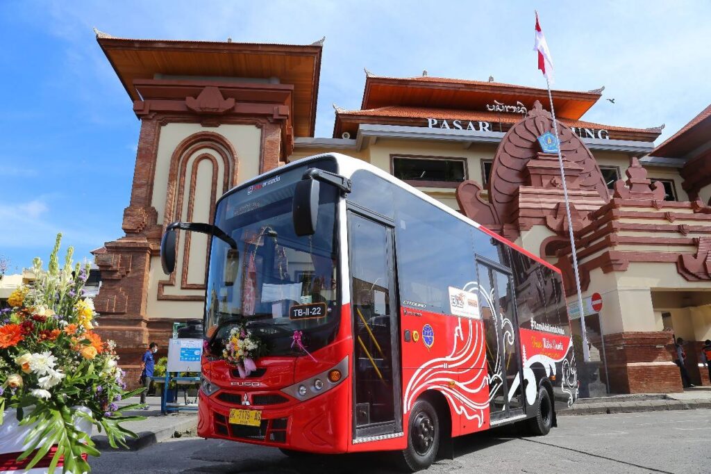 "Red Bali tourism bus in front of traditional Balinese architecture at Denpasar"
