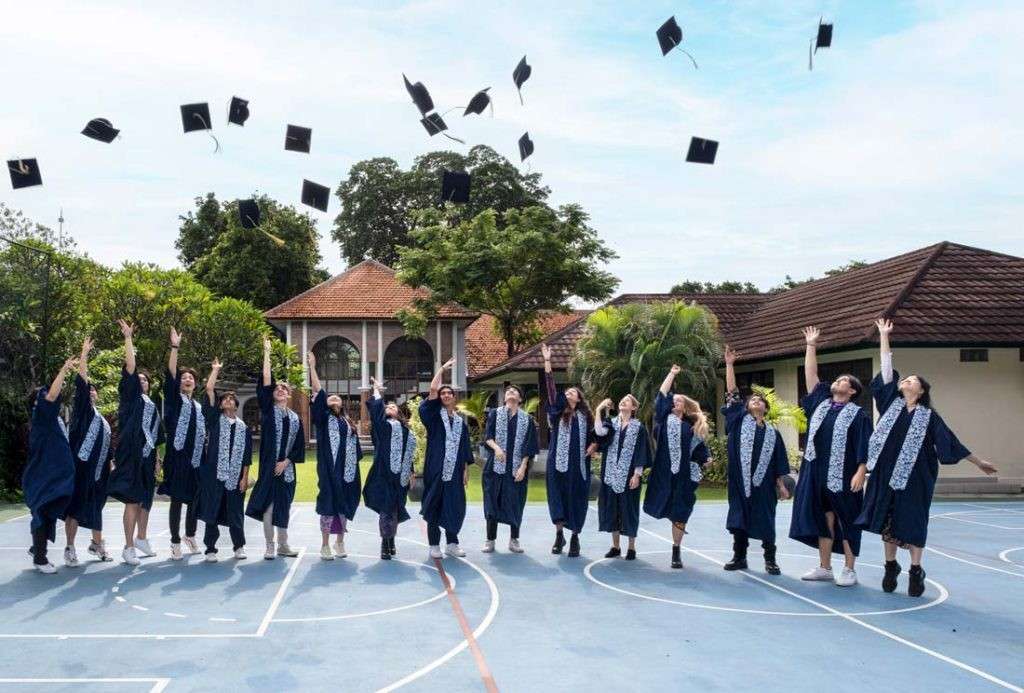 "High school graduation ceremony in Bali with students throwing caps into the air"